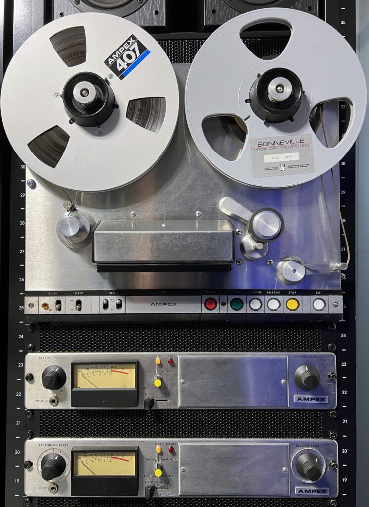 A silver and black tape recorder on top of a shelf.