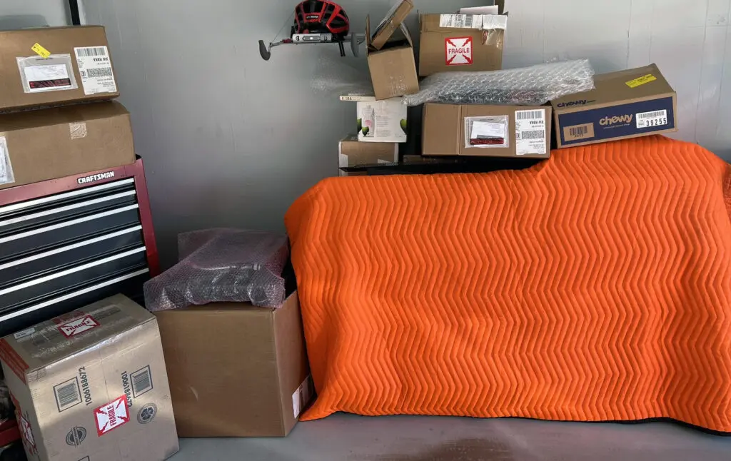 A bed with an orange blanket and some boxes