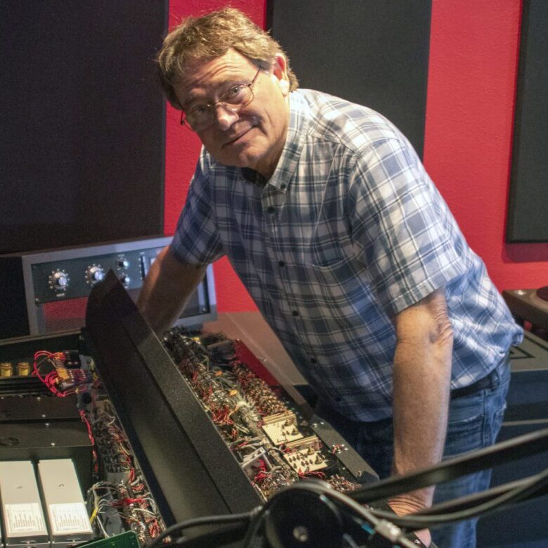 A man standing next to an instrument in a recording studio.