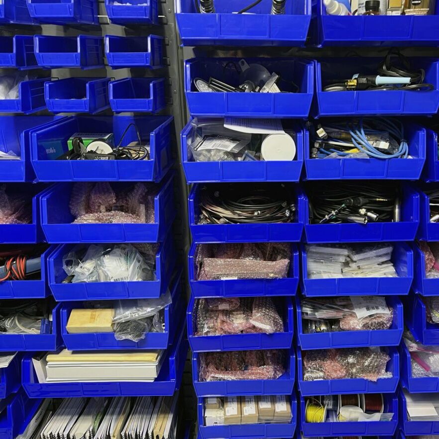 A wall of blue bins filled with different types of items.